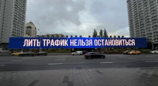 Уличный билборд с крупной надписью «Лить трафик нельзя остановиться» на фоне жилых высоток, проезжей части и пасмурного неба.