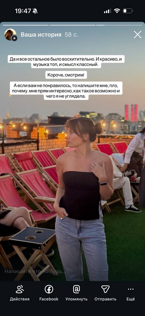 Фото на крыше в вечернем городе: девушка в чёрном топе и джинсах, ряды шезлонгов и мягкая городская подсветка на заднем плане.
