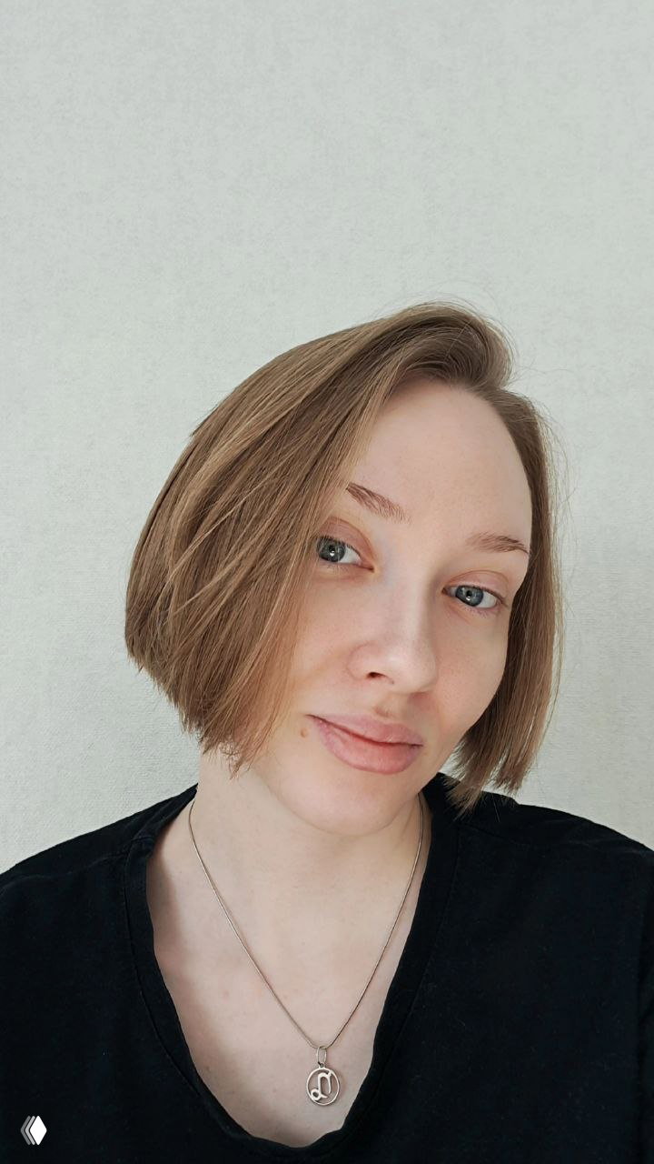 Портрет женщины с короткой стрижкой на светлом фоне, спокойное нейтральное выражение лица, кадр по верхнюю часть корпуса.