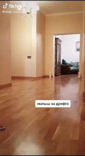 Широкий план коридора с блестящим паркетом или ламинатом и подписью «малыш на дрейфе», демонстрирующий, как легко можно скользить по такой поверхности.