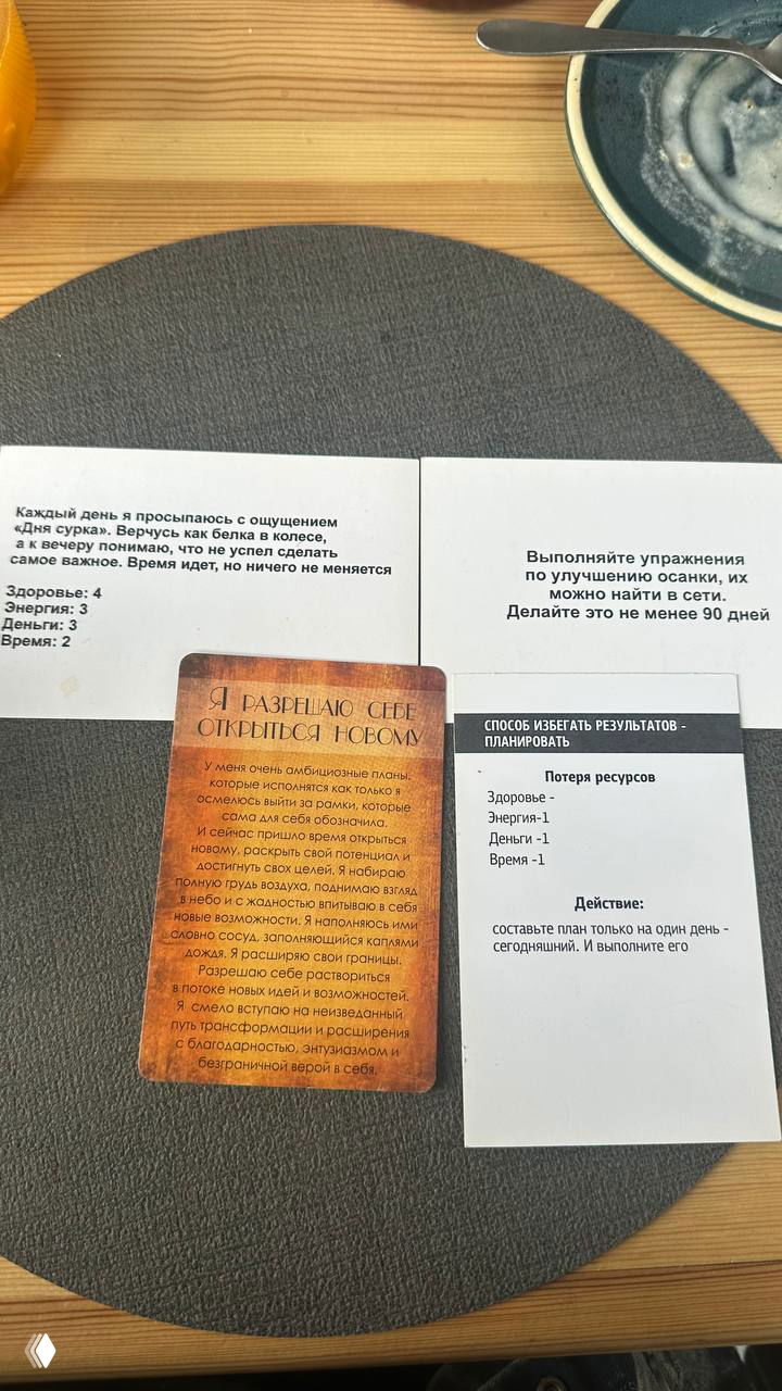 Метафорическая карта и распечатанные карточки с текстом упражнений на деревянном столе; видна структура заданий и посуда вокруг.