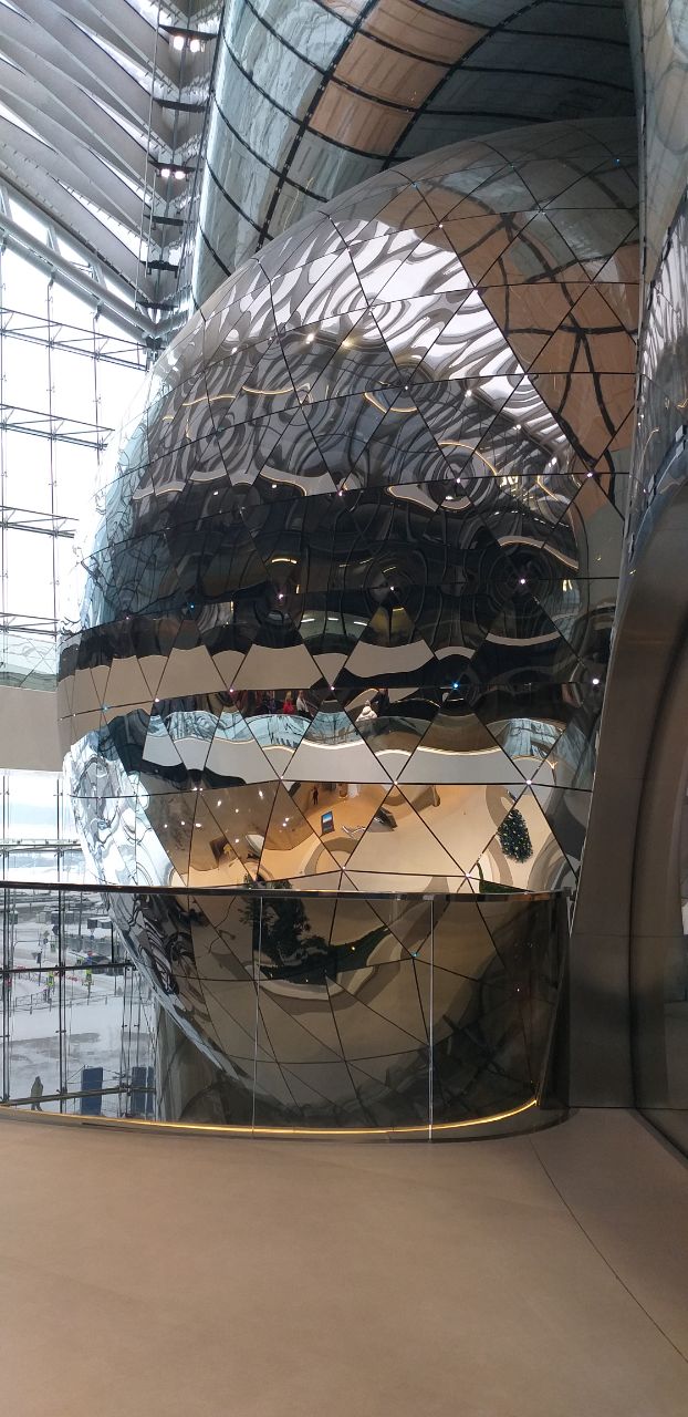 Фасетированная большая отражающая скульптура или структура в холле Лахта‑центра с множеством зеркальных граней и отражений пространства.