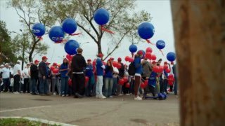 Колонна участников шествия в Благовещенске с синими и красными шарами; сотрудники в фирменной одежде отмечают 170‑летие города.