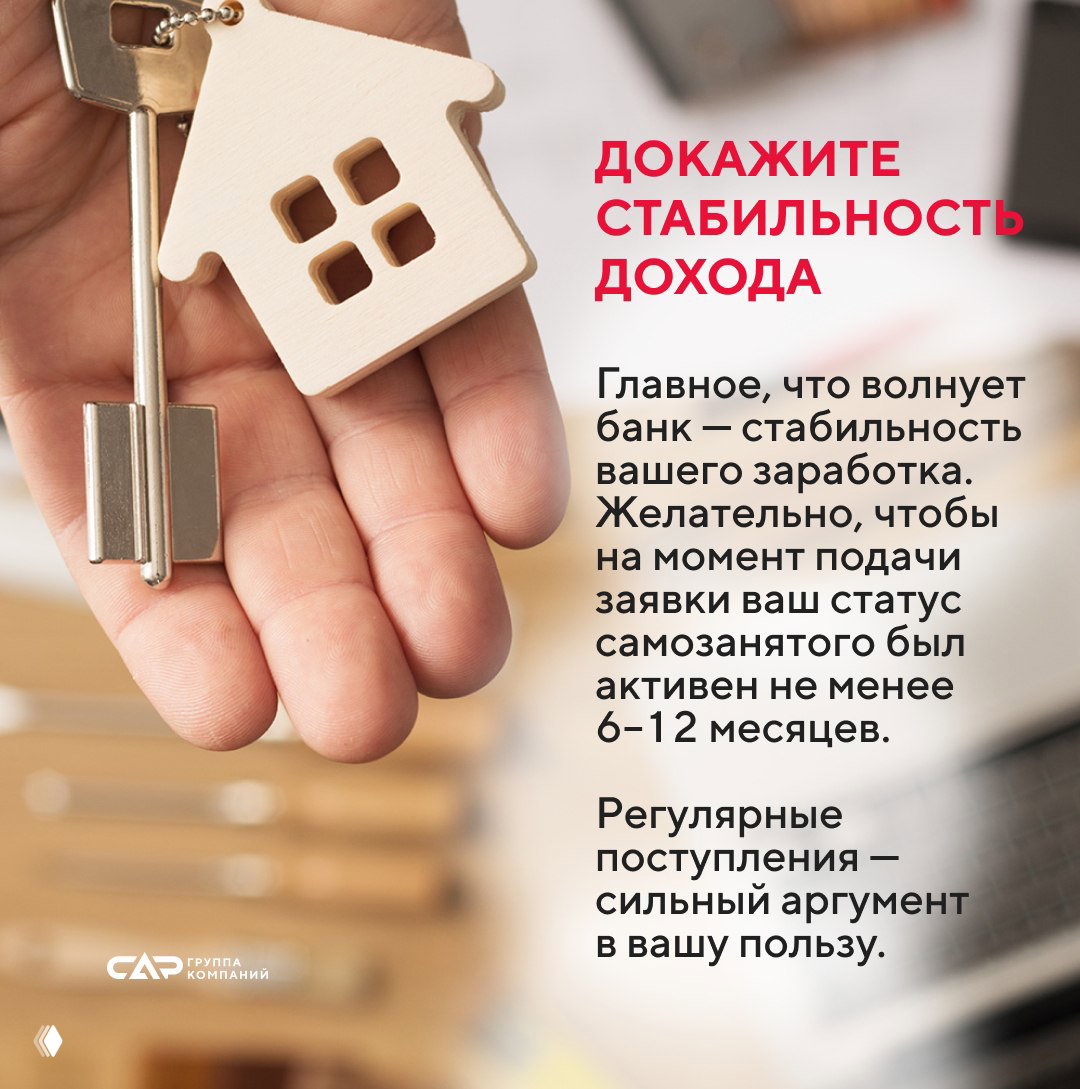 Крупный план ладони с деревянным брелоком в форме дома и ключом; иллюстрация к советам о подтверждении стабильности дохода для банков и требований к стажу.