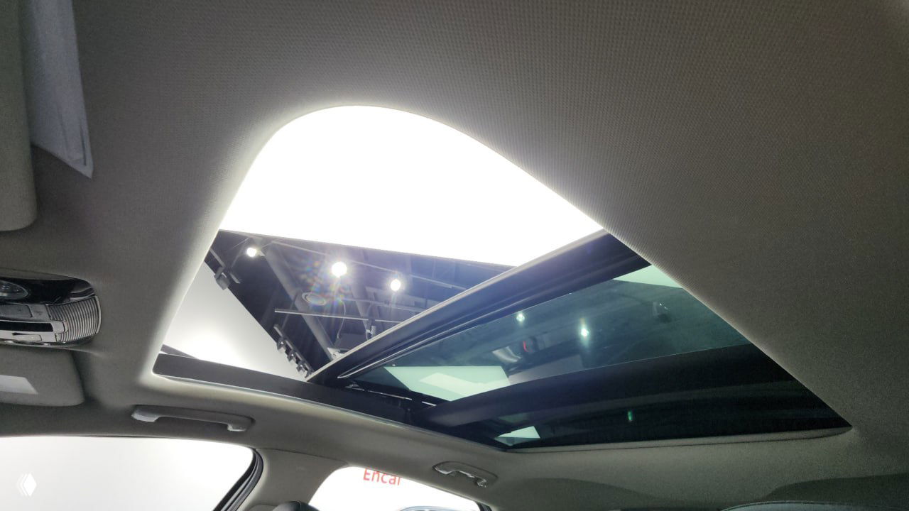 Панорамный люк и потолочная обшивка Kia K5: открытый люк, стеклянная секция и элементы освещения студии на отражении поверхности