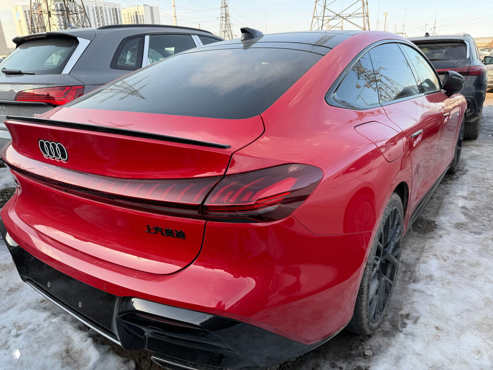 Боковой и задний ракурс красной Audi A5L на стоянке, видно контур купеобразного кузова и воздуховоды заднего бампера.