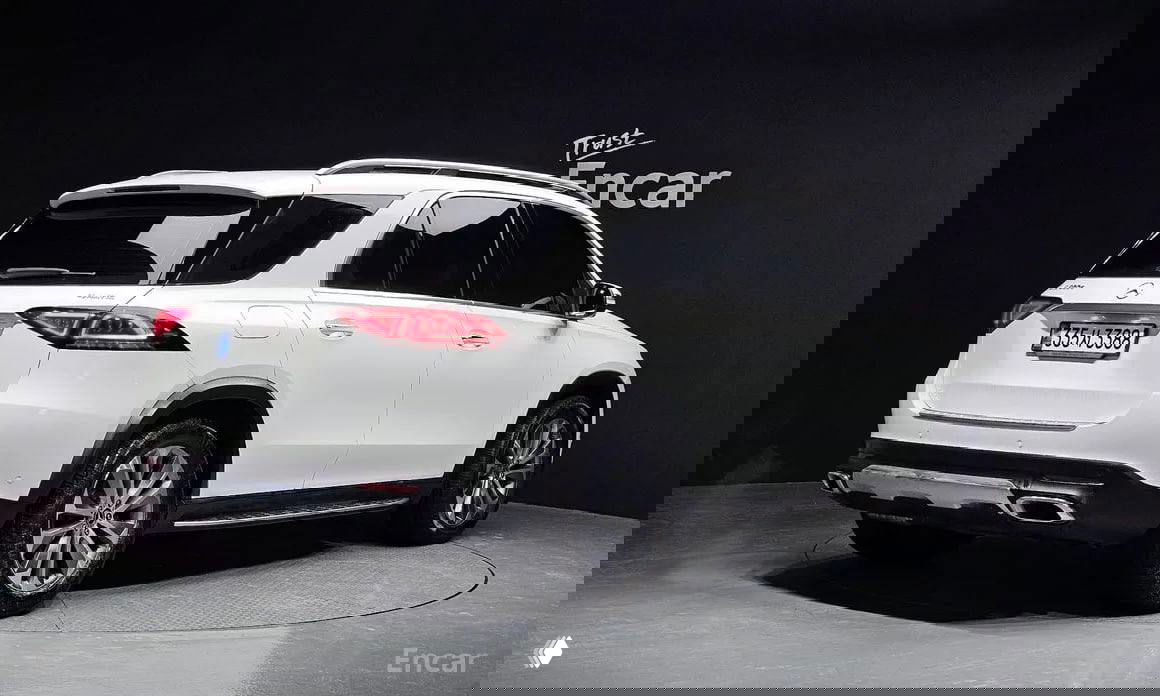 Белый Mercedes‑Benz GLE‑Class W167, вид сзади‑сбоку в выставочном зале, видна задняя часть автомобиля и задние фонари.