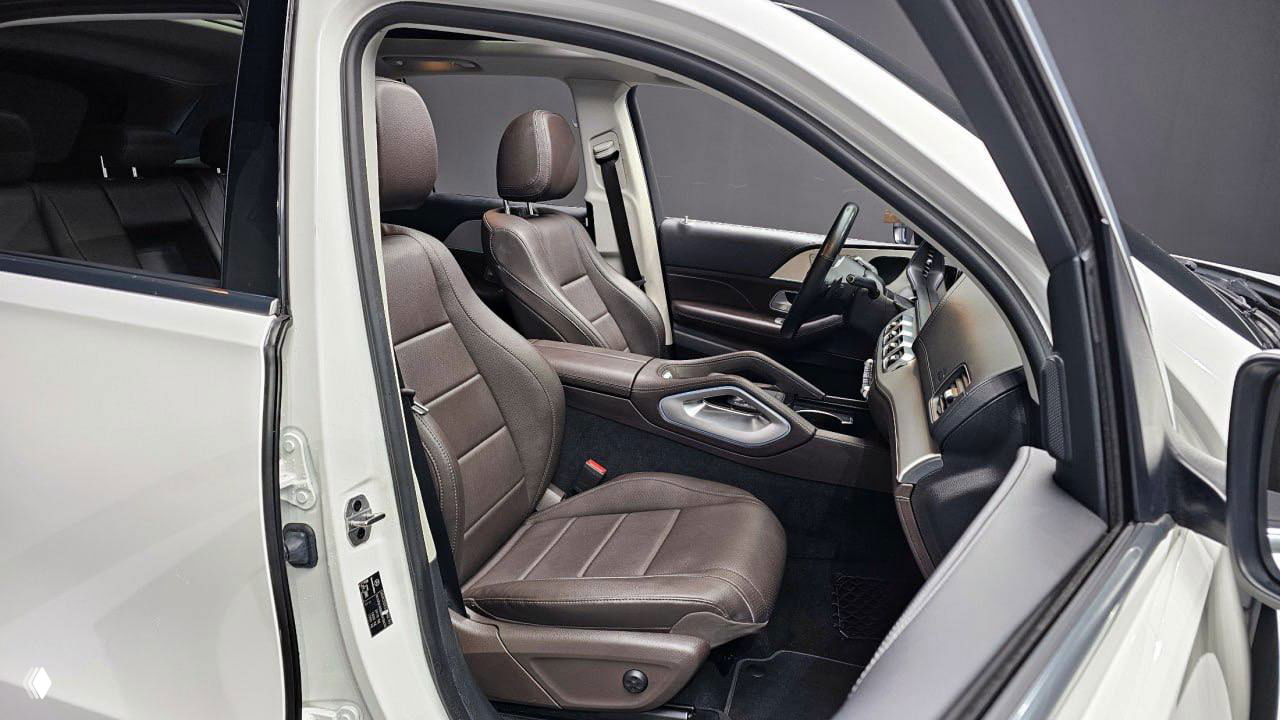 Интерьер Mercedes‑Benz GLE: передние сиденья коричневой кожи, открытая передняя дверь и вид на приборную панель с пассажирской стороны.
