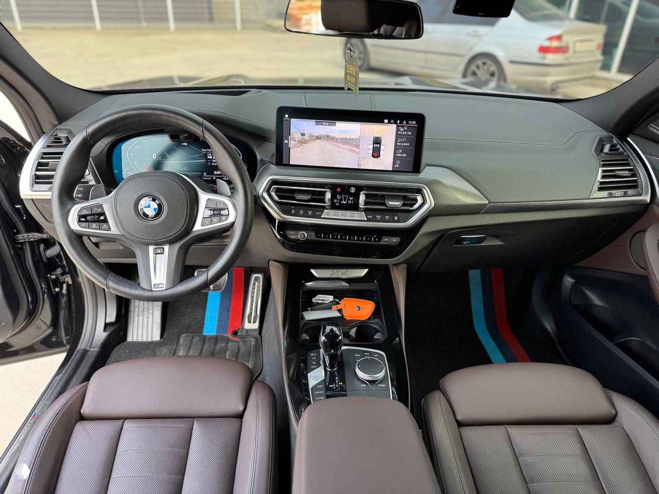 Вид на переднюю панель и центральную консоль BMW X4: мультимедийный дисплей, элементы управления климатом и селектор коробки передач.