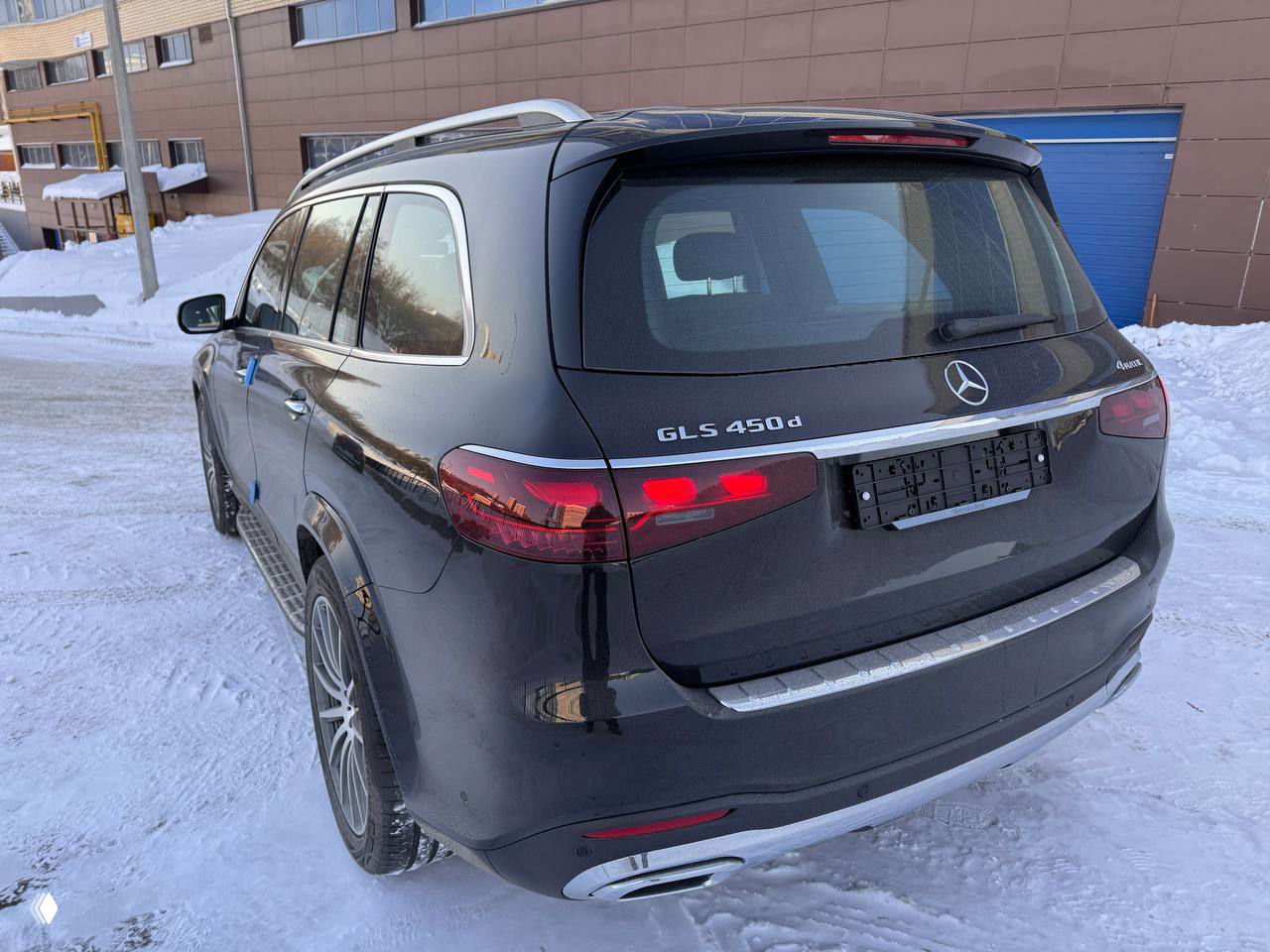 Задняя часть Mercedes‑Benz GLS 450d 2025 на снегу, шильдик GLS 450d виден на крышке багажника, считываются элементы бампера и комбинированные фонари.