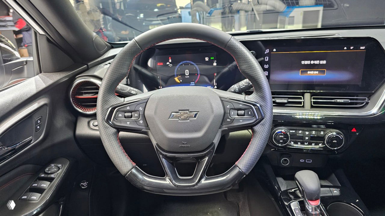 Вид из кабины на руль и панель приборов Chevrolet Trax: мультируль с логотипом Chevrolet, цифровая приборная панель и центральный экран.