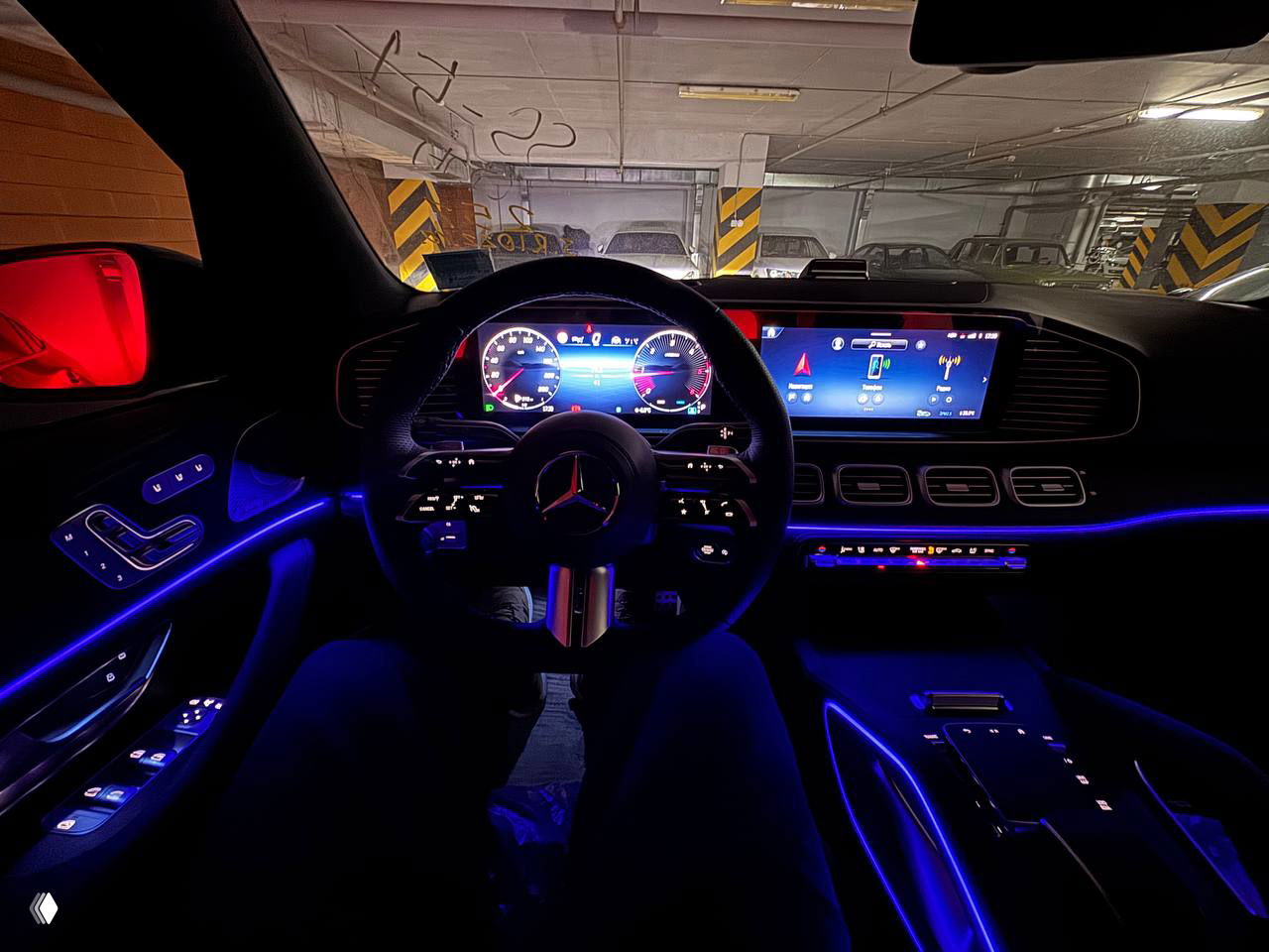 Салон Mercedes‑Benz GLS с подсветкой Ambien Light ночью: панель приборов, большой центральный экран и фиолетовая акцентная подсветка по интерьеру.