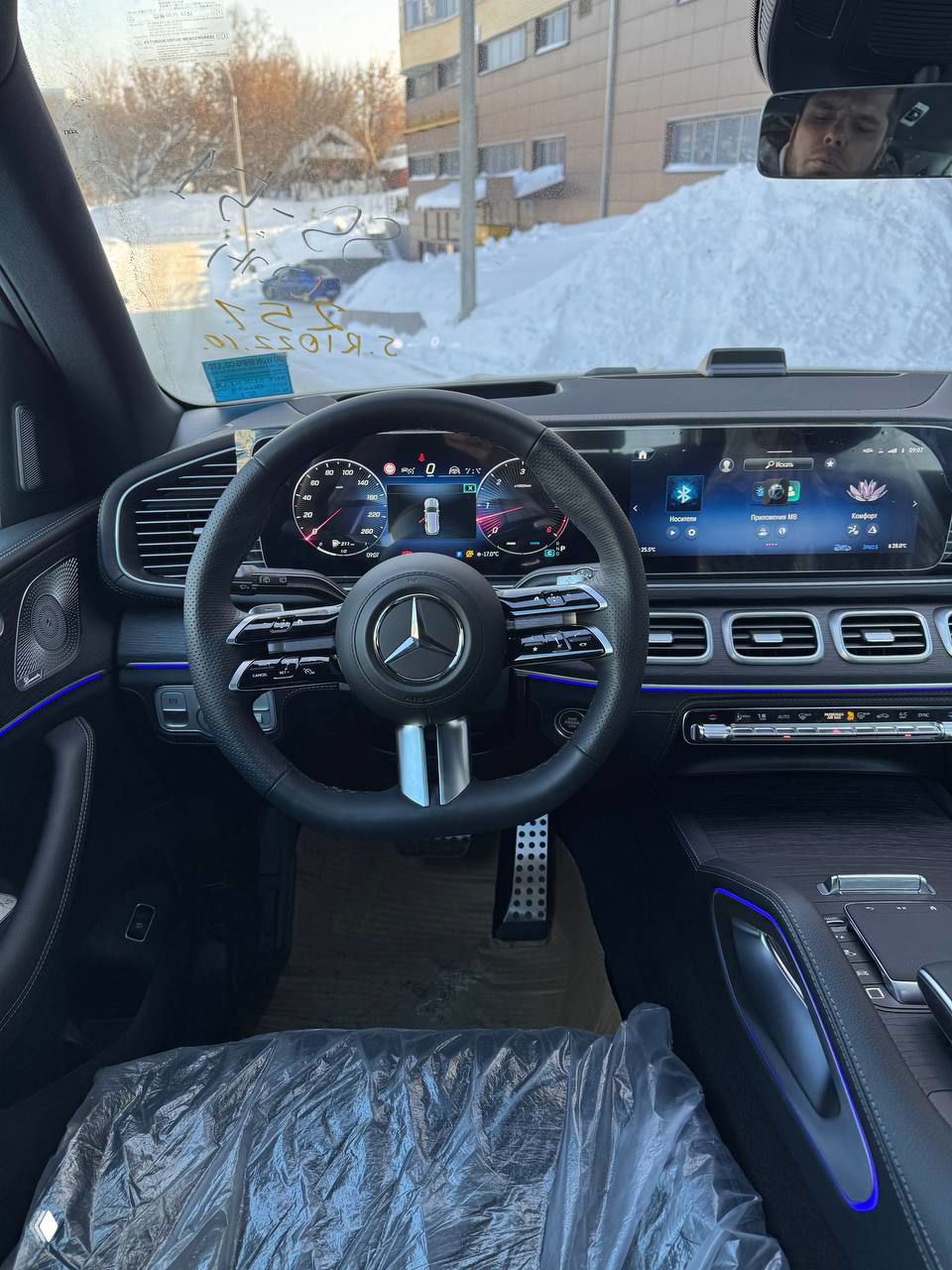 Салон Mercedes‑Benz GLS 450d с открытой передней дверью: вид на переднее пассажирское пространство, накладки дверей и элементы управления сиденьями.