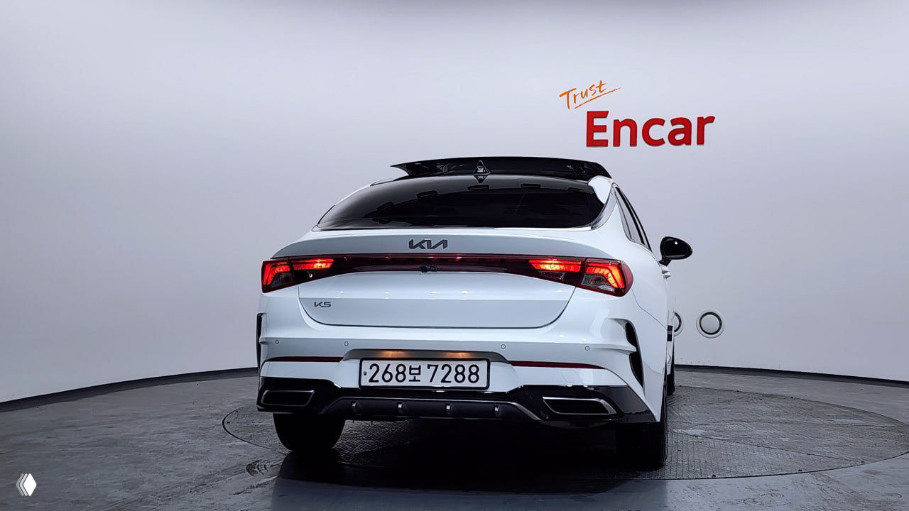 Задняя проекция белого Kia K5 на поворотном подиуме Encar: светодиодная оптика, бампер, вид на крышу и корейский номер автомобиля