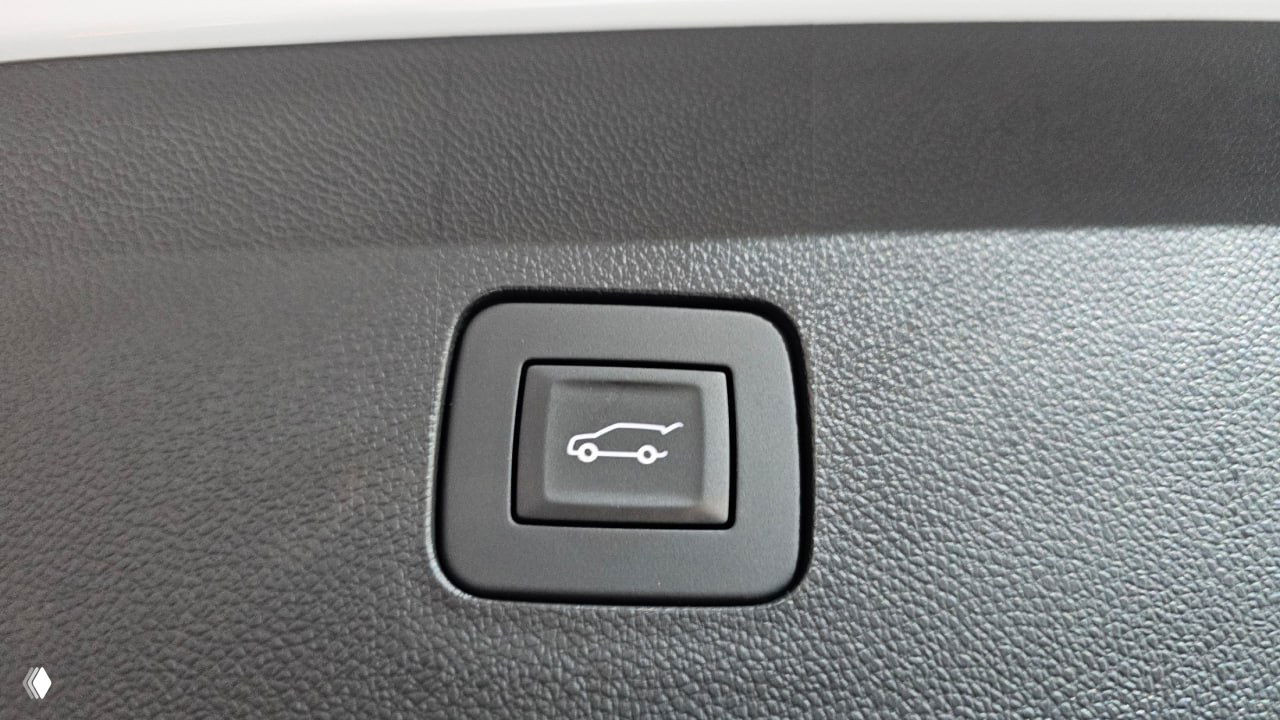 Кнопка открывания багажника на внутренней отделке крышки багажника автомобиля крупным планом, значок автомобиля с открытым багажником.