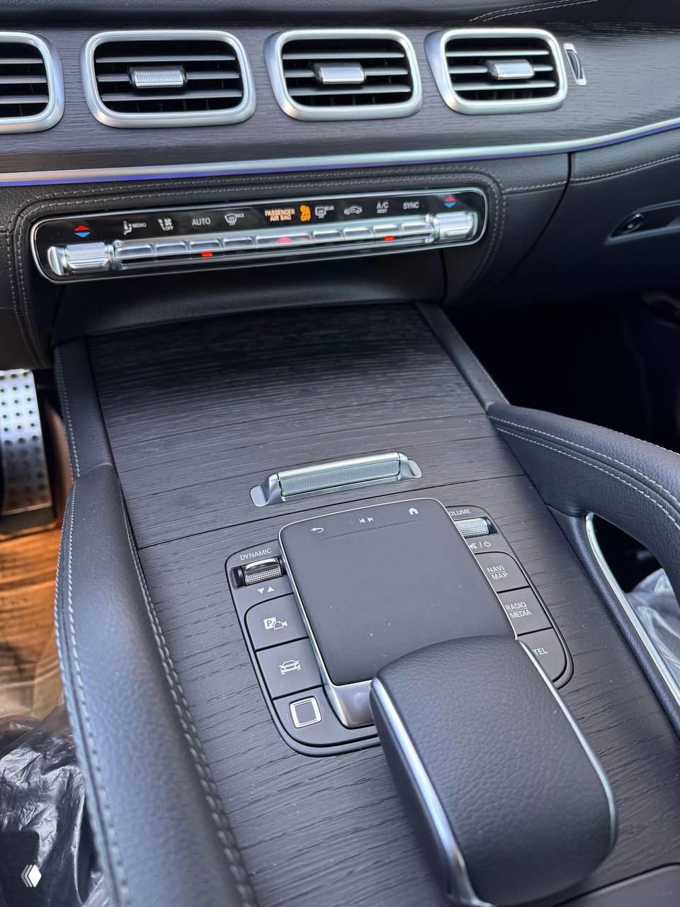 Крупный план панели двери с регулировкой сидений и декоративной решёткой акустики Burmester, видна подсветка и отделка из тёмного дерева/материала.