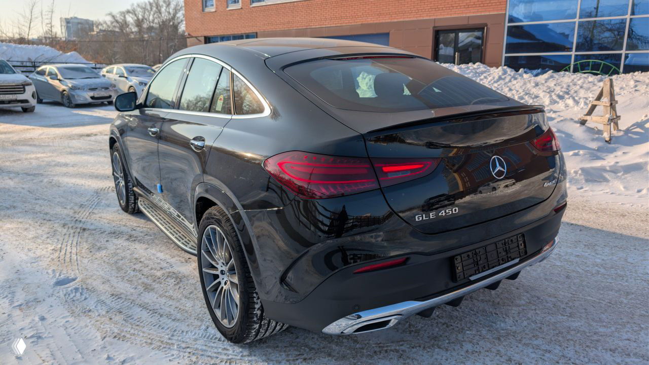 Тыльная часть Mercedes GLE 450 — вид сзади на снежной парковке, видны задние фонари, шильдик GLE 450 и дорожная поверхность зимой.