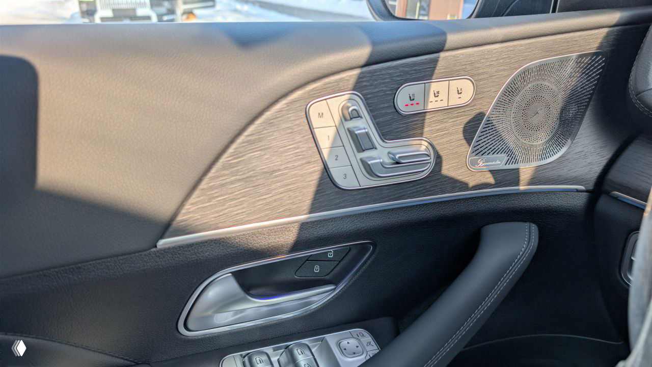 Деталь дверной панели Mercedes GLE: панель управления положением сиденья, кнопки памяти и декоративная отделка с динамиком, вид близко.
