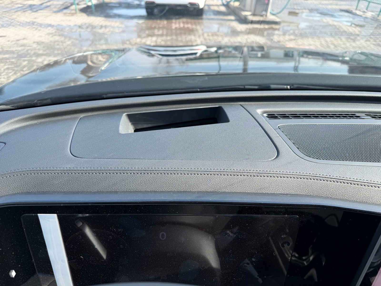 Крупный план торпеды и лобового стекла Tiguan L Pro: отделка торпеды, вентиляционные решётки и вид через лобовое стекло на стоянку.