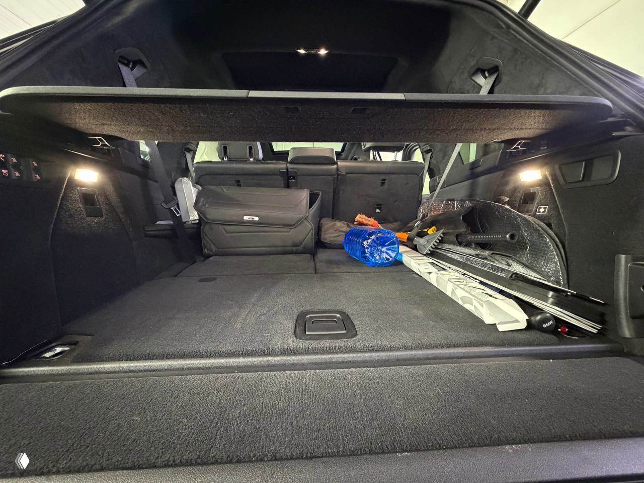 Багажное отделение BMW X7 с разложенными сиденьями и грузом, демонстрируется объём багажника и состояние обшивки багажного отделения.