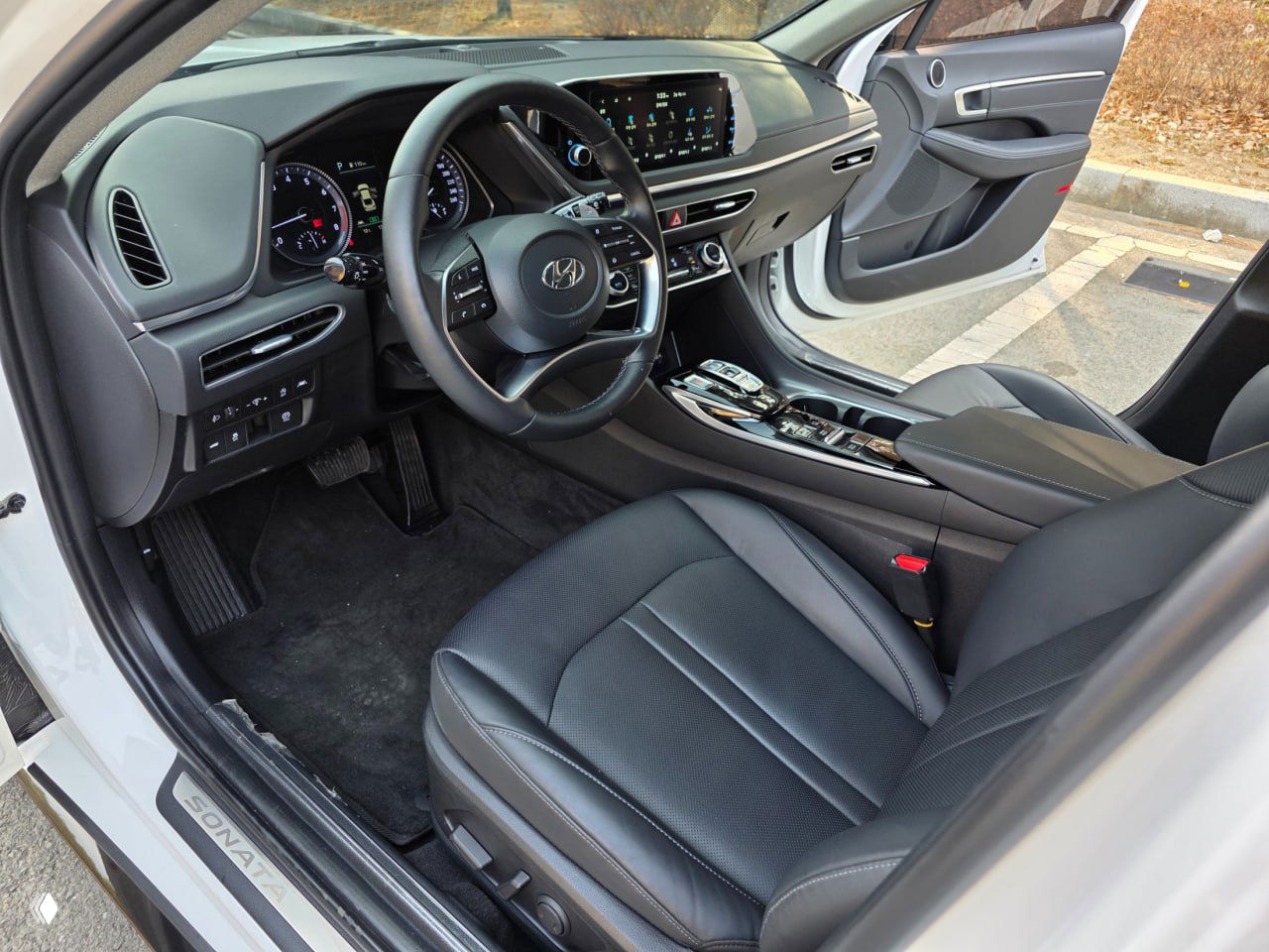 Интерьер водительской части Hyundai Sonata: рулевое колесо, приборная панель и центральный экран мультимедиа в чёрной отделке.