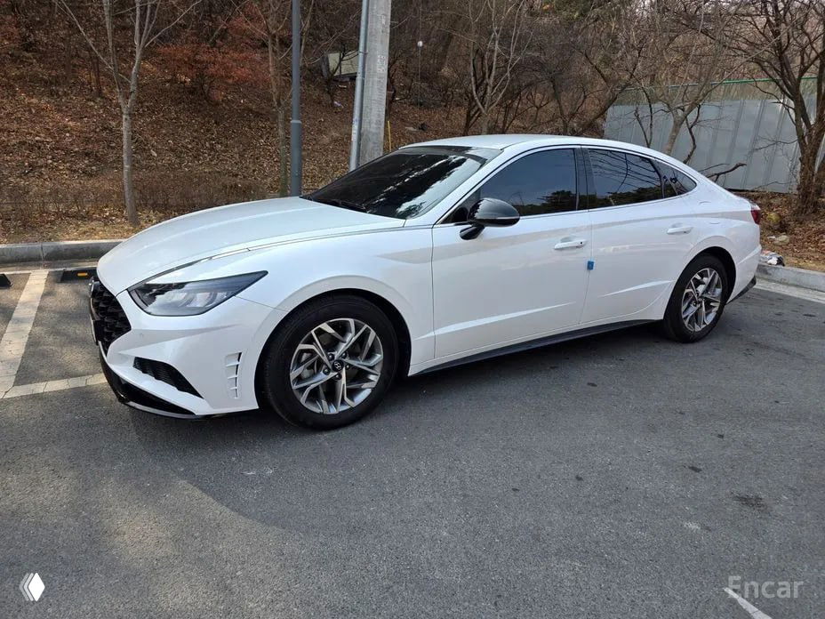 Профиль белого Hyundai Sonata DN8 на стоянке; видна боковая линия кузова, колёсные диски и затемнённые стекла автомобиля.