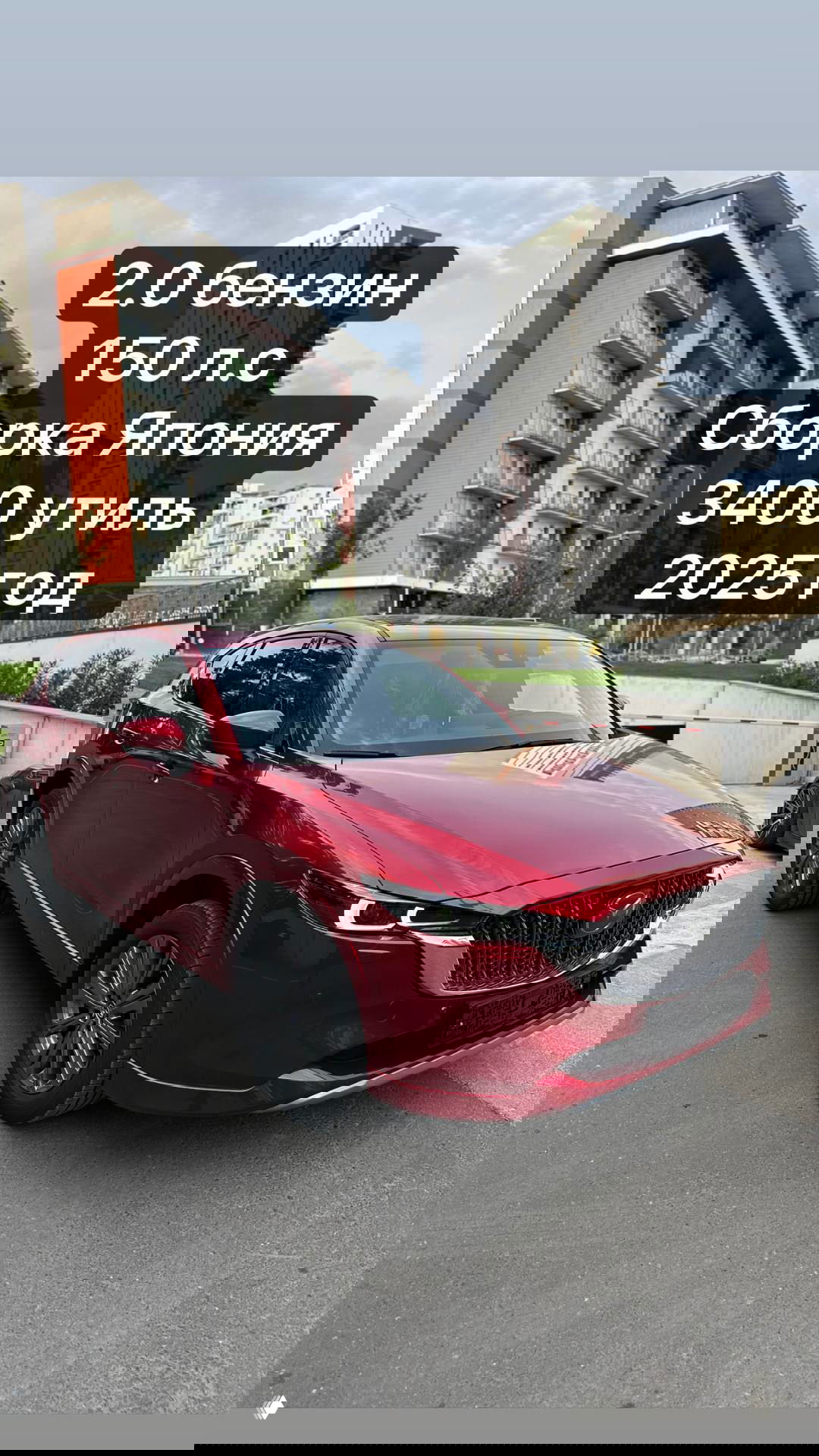 Красная Mazda CX-5 2025 припаркована на фоне жилых домов; крупный план кузова и решётки радиатора, на фото наклейка с указанием утилиз. сбора 3400 руб.
