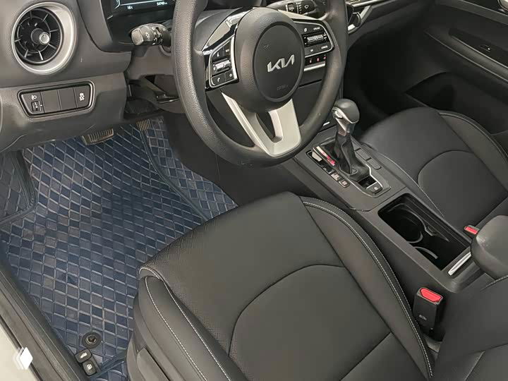 Передние сиденья и часть пассажирского пространства Kia K3 — видна обивка, состояние сидений и напольные коврики в салоне автомобиля.