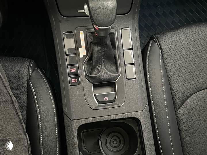 Блок переключения передач и посадочная зона между передними сиденьями Kia K3: рычаг, кнопки и подстаканник видны в крупном плане.