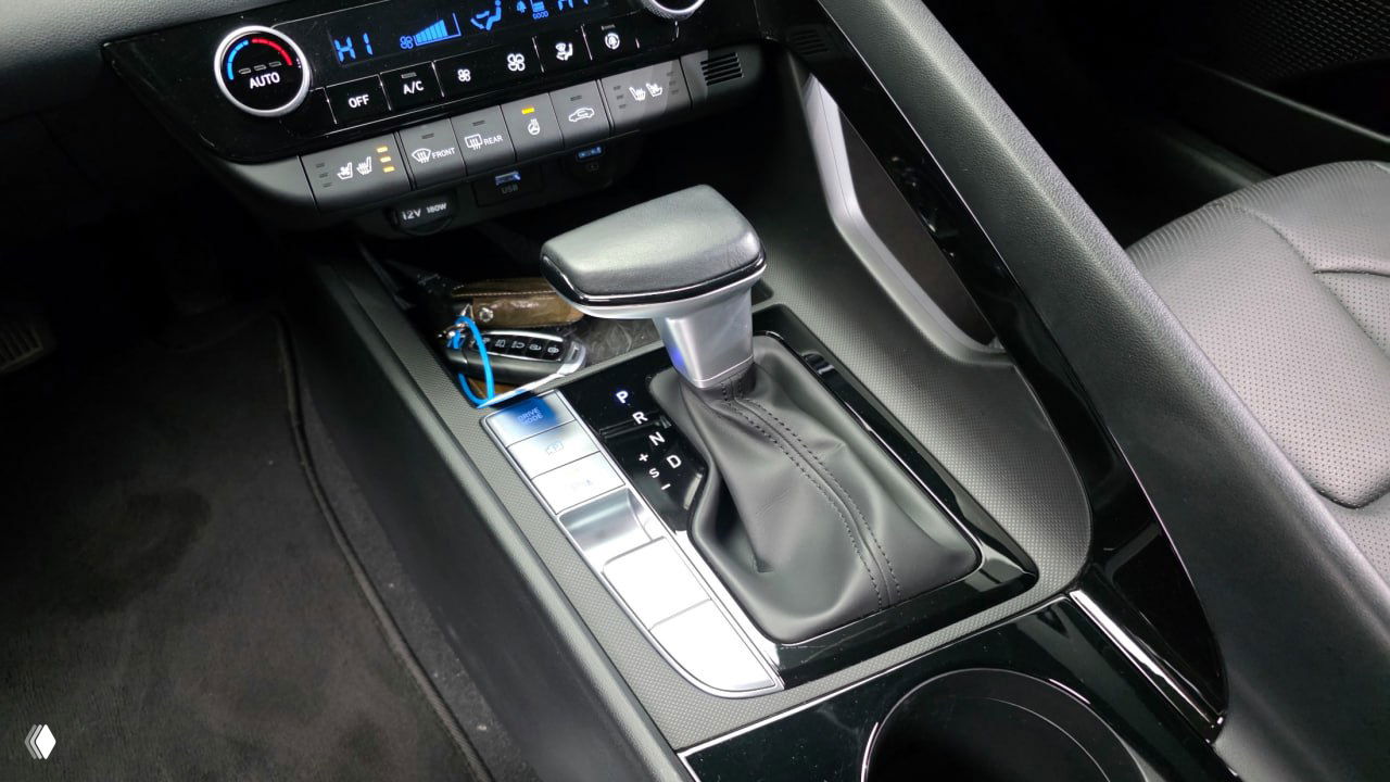 Крупный план центральной консоли Hyundai AVANTE: селектор коробки передач CVT, подстаканники и элементы управления климатом вблизи.