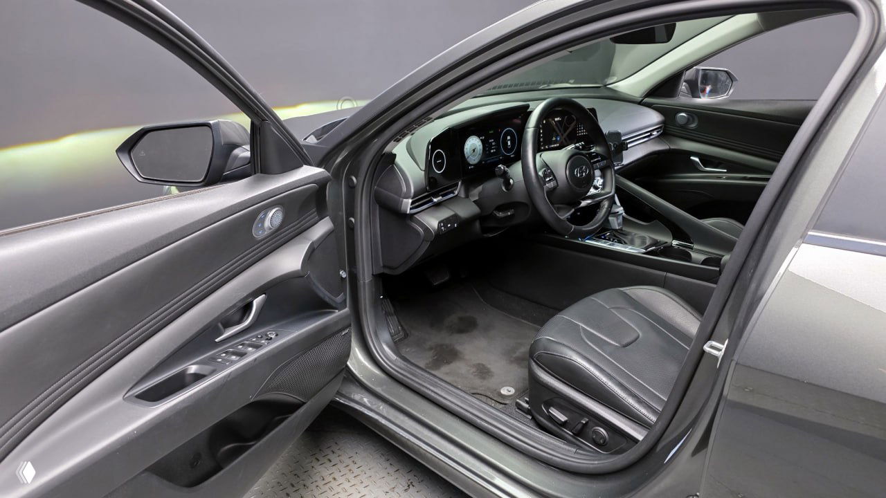 Вид на водительскую дверь и сиденье Hyundai AVANTE с электроприводом и регулировками памяти, видна обивка и подлокотник в темной отделке.