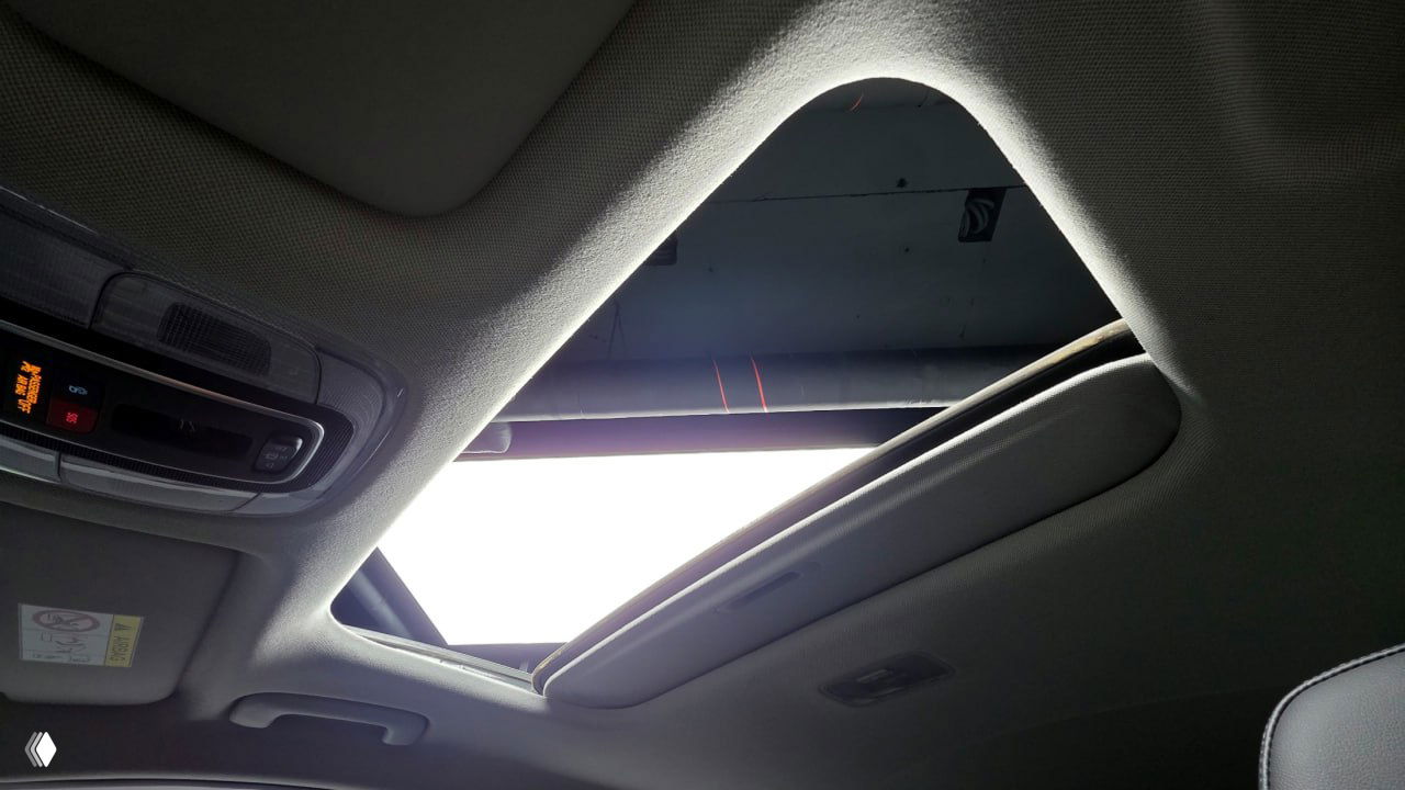 Снимок крыши с люком Hyundai AVANTE: открытый люк и фрагмент панелей управления светом на потолке, вид из салона вверх.