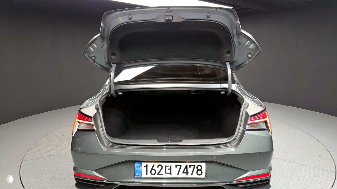 Фото багажного отсека Hyundai AVANTE с открытой крышкой: пустой и чистый багажник, вид на заднюю часть автомобиля и номерной знак корейской регистрации.