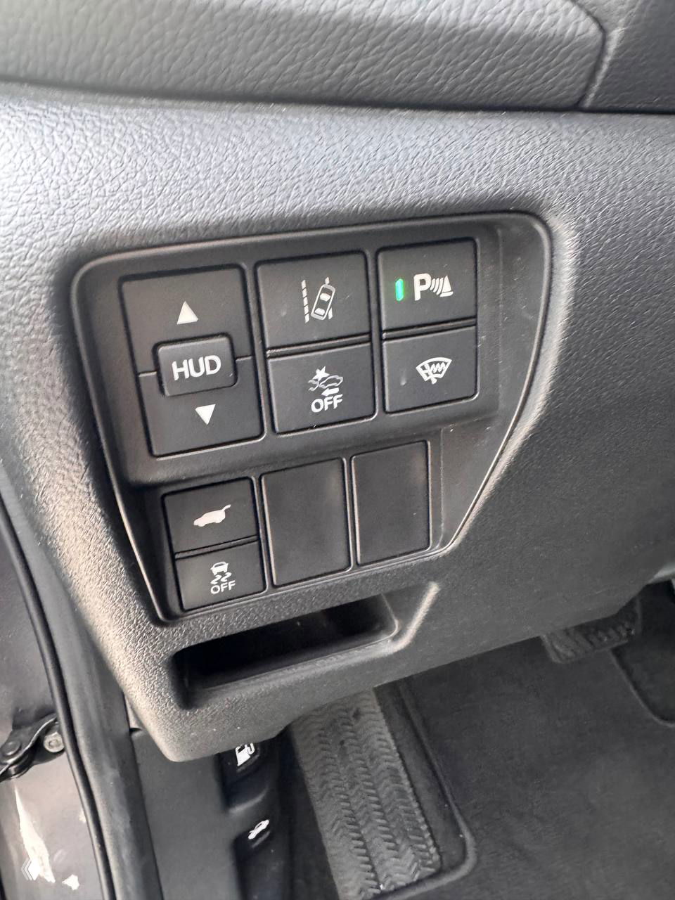 Блок кнопок и переключателей слева от руля в Honda CR‑V 2021: HUD, системы помощи и кнопки управления функциями автомобиля крупным планом.