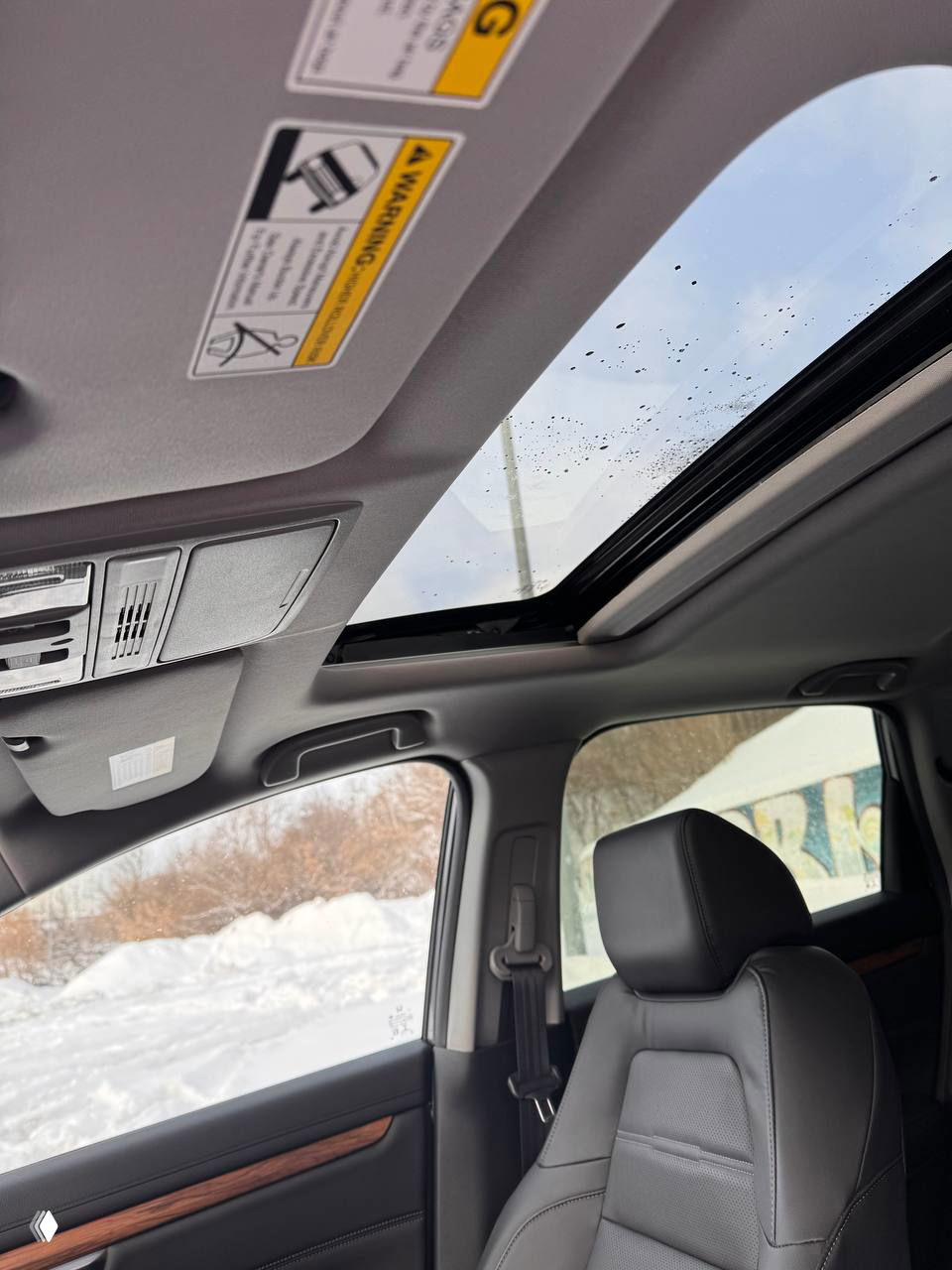 Открытый люк‑панорамный верх в салоне Honda CR‑V 2021: вид на небо через стеклянный люк и переднее пассажирское сиденье в кадре.