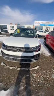 Фронтальный кадр белого Volkswagen Tharu 2025 на стоянке дилера; видна решётка радиатора, фары, снег на земле и соседние авто.