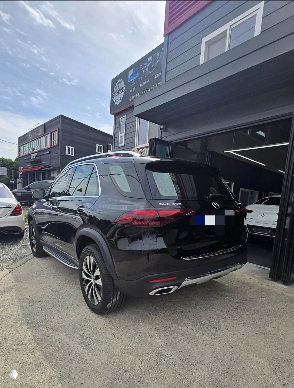 Чёрный Mercedes‑Benz GLE‑Class 350i, вид сзади‑сбоку: багажник, шильдик GLE 350 и внешнее состояние автомобиля на площадке дилера.