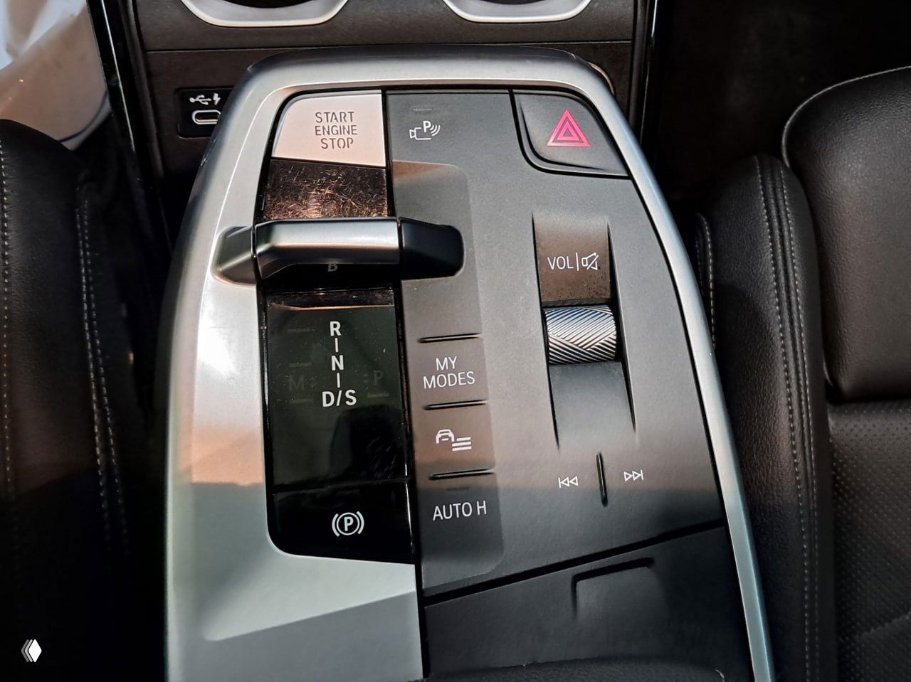 Ближний план центральной панели управления BMW X1: селектор коробки передач, кнопки My Modes, регулятор громкости и элементы управления парковкой.