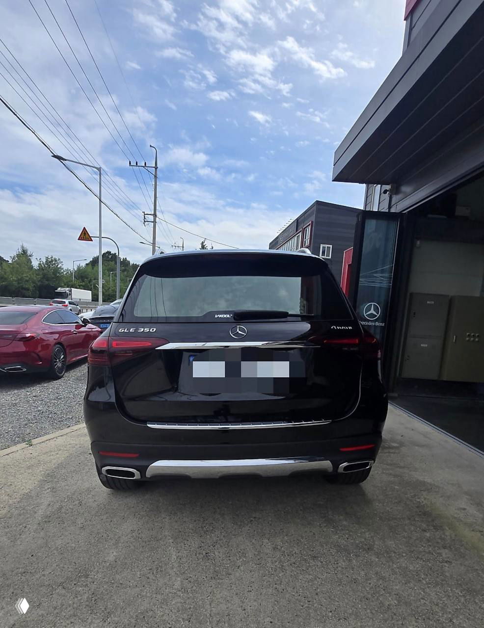 Вид сзади на чёрный Mercedes‑Benz GLE‑Class 350i, изображение показывает задний бампер, выхлопные насадки и номерной знак, частично закрыт.