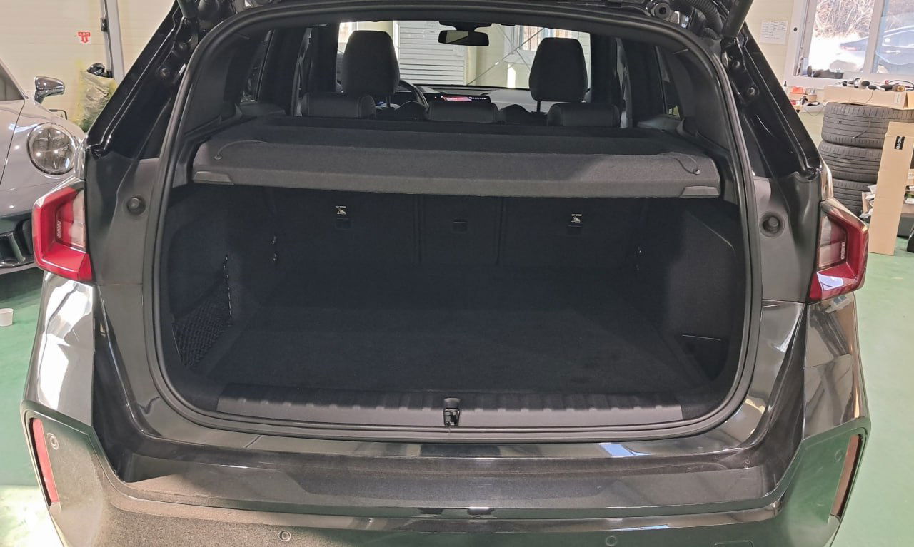 Открытый багажник BMW X1 с видимой грузовой площадью и откидной шторкой: чистое пространство в грузовом отделении для перевозки вещей.