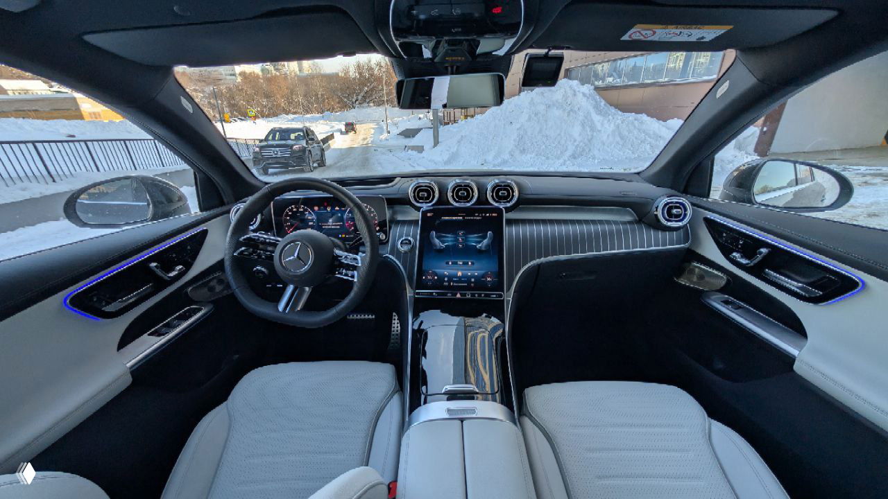 Интерьер Mercedes GLC 300 Coupe: панорамный вид салона спереди, руль, центральная консоль и большой сенсорный экран, светлая отделка сидений