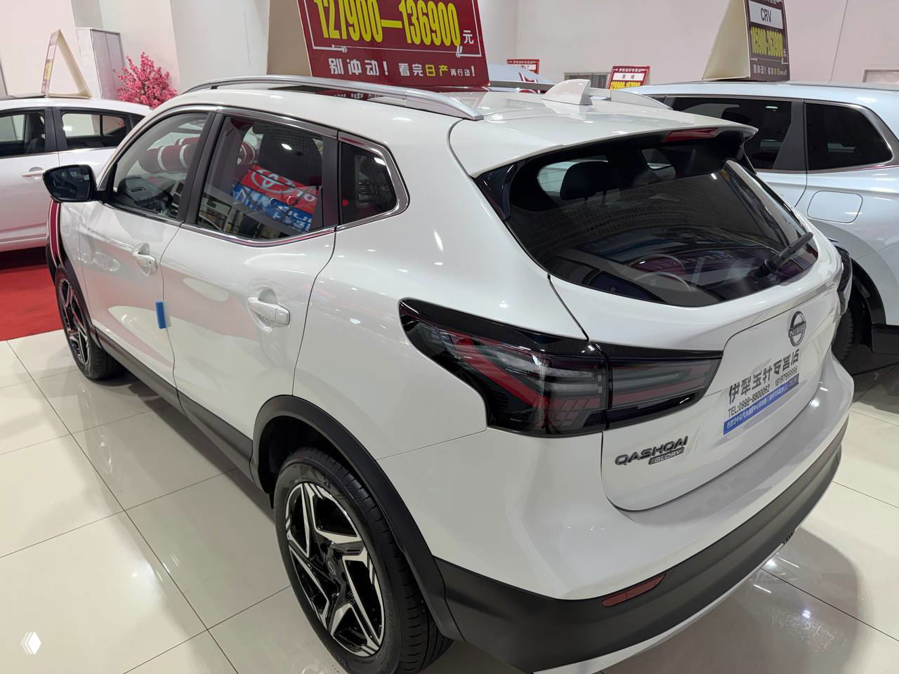 Угол сзади и сбоку белого Qashqai: чёрные защитные накладки, модернизированные фонари и отражения на глянцевом покрытии кузова.