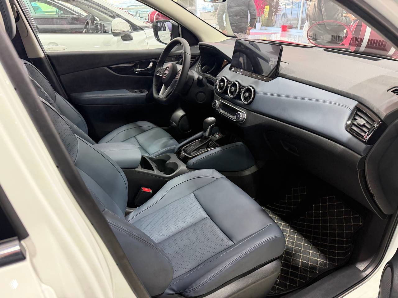 Другой ракурс задней части и колёс белого Nissan Qashqai в салоне, подчёркивающий дизайн багажника и линию крыши.