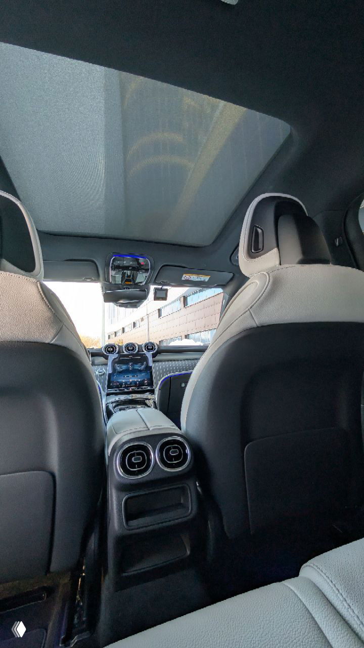 Вид из задней части салона на панорамную крышу и пространство между передними сиденьями Mercedes GLC 300, электрические дефлекторы и внутреннее освещение