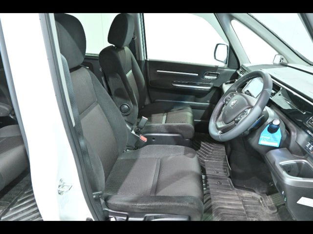 Передние сиденья и водительское место Honda Step Wagon: тканевая обивка, подлокотники, руль и общий вид посадочных мест и пола салона.