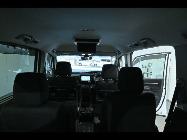 Вид из середины салона на заднюю часть Honda Step Wagon: третий ряд сидений, потолочный монитор и пространство багажного/пассажирского отделения.