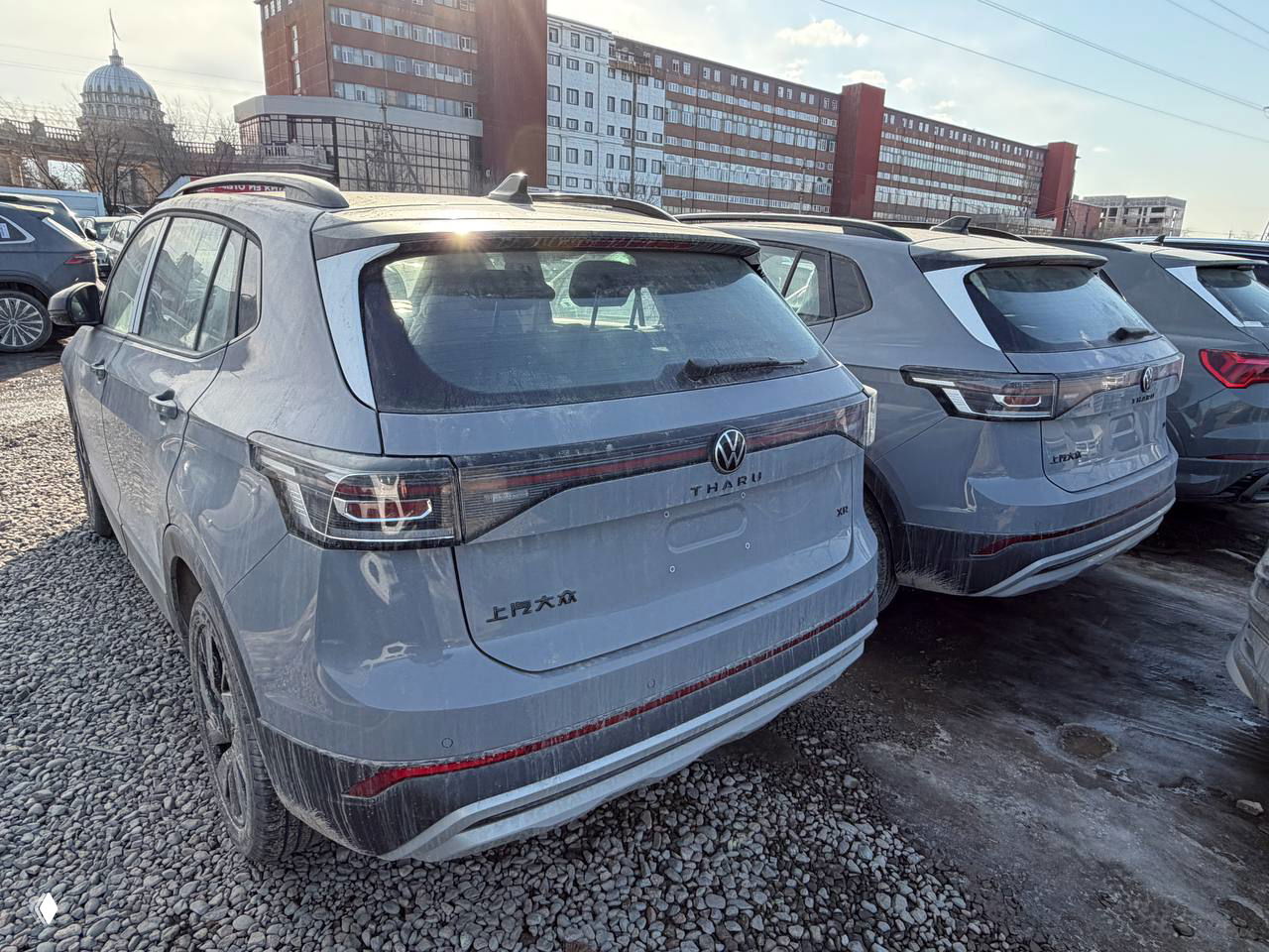 Вид сзади на Volkswagen Tharu XR на гравийной площадке, видна надпись THARU на крышке багажника и следы грязи на бампере и порогах.