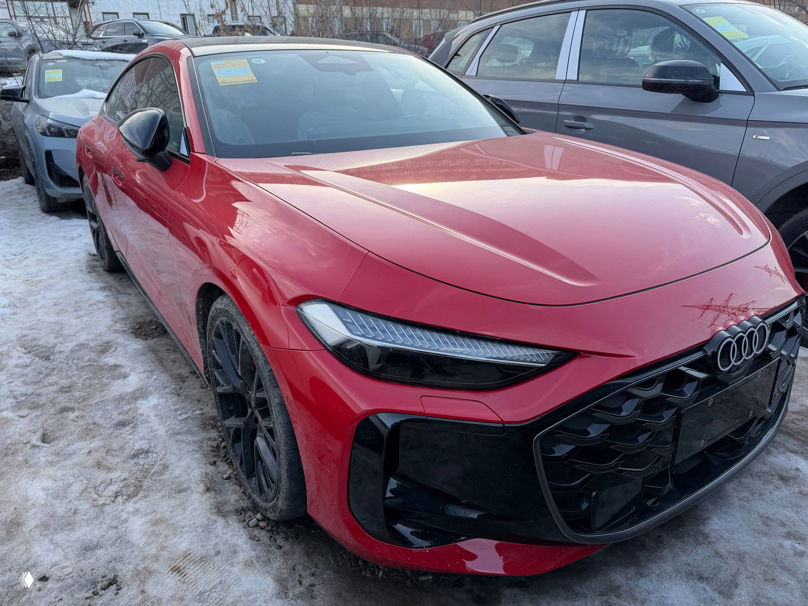 Красная Audi A5L на уличной стоянке, крупный план передней правой части, видны чёрные колёсные диски и грязь на кузове.