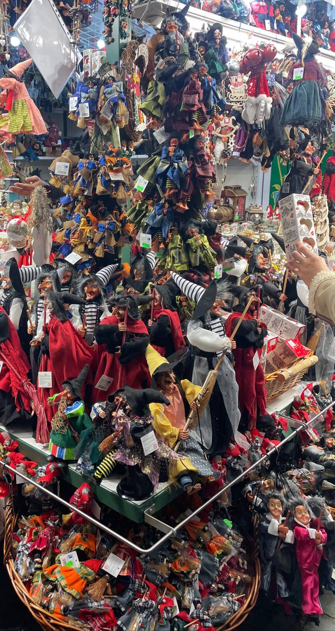 Торговая точка с множеством кукольных фигур и сувениров на римском рождественском базаре, плотная выкладка товаров и посетители.