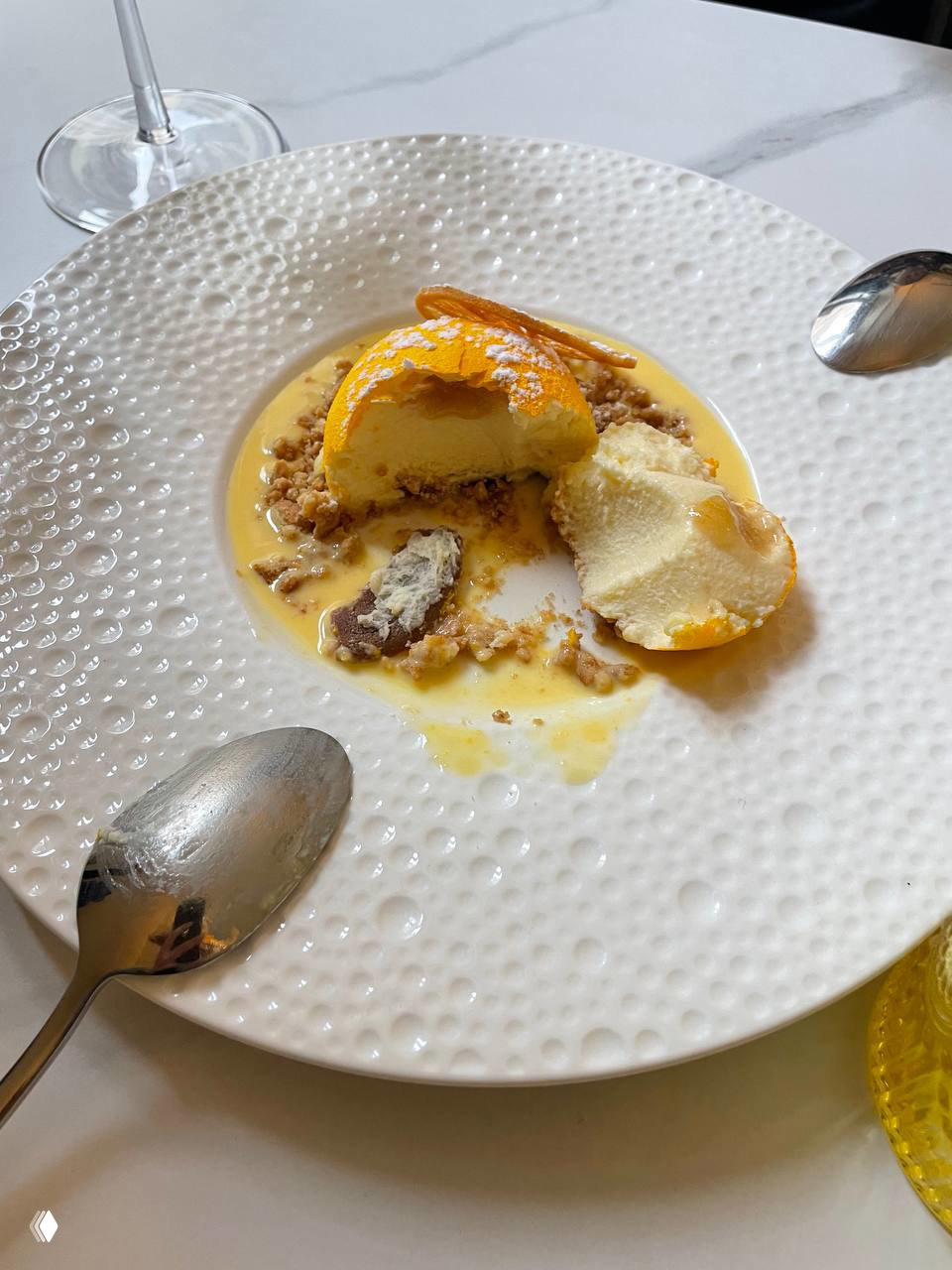 Десерт на белой тарелке с соусом, крошками и двумя ложками — кадр из кафе или ресторана во время путешествия по Сицилии.